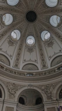 Yuvarlak çatı pencereleri, yontulmuş kabartmalar ve doğrudan aşağıdan görünen dekoratif detaylarla dolu barok tarzı bir kubbe..