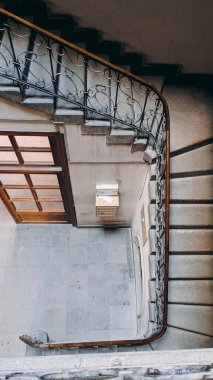 Eski bir spiral merdiven boşluğunun yukarıdan görünüşü dekore edilmiş demir parmaklıklar ve yerleşim yerinin döşemeleri..