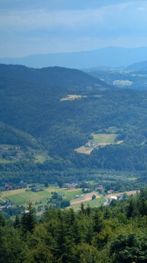Yazın küçük kırsal köyü, orman tepeleri ve tarlaları olan manzaralı dağ vadisi. Fotokopi alanı ile güzel doğa arka planı, seyahat ve yaşam tarzı kavramı.