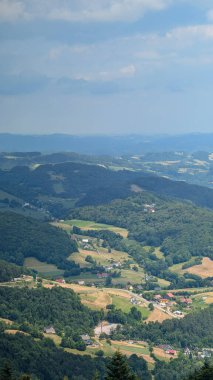 Mavi gökyüzünün altında küçük evleri, tarlaları ve orman tepeleri olan görkemli kırsal dağ vadisi. Güzel yaz manzarası, seyahat ve fotokopi alanı ile yaşam tarzı.