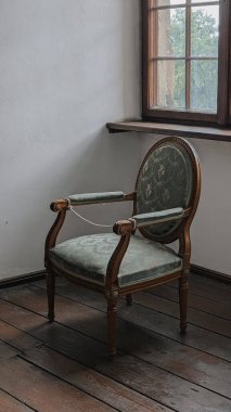 Pencerenin yanındaki antika, ahşap koltuğun içinde yeşil döşemeler var. Tarih, miras, dekor ve klasik tasarım kavramları için mükemmel..