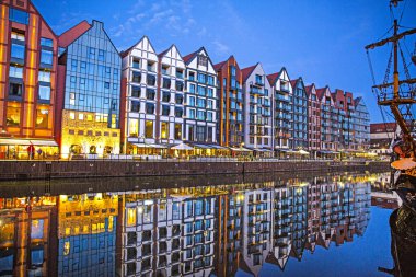 Polonya 'nın eski Gdansk kasabasındaki Motlawa nehrinde gece ışıkları yankılanıyor. Modern ve eski eşyalar birlikte. 