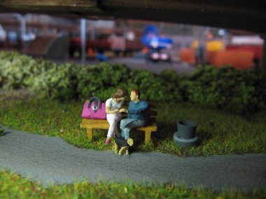 Aşıklar bankta oturur ve köpek onların yanında durur.