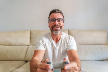 Evdeki kanepede video oyunları oynarken gülümseyen orta yaşlı adamın ön görünümü