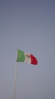 Meksika bayrağı mavi gökyüzüne karşı gün batımında dalgalanıyor