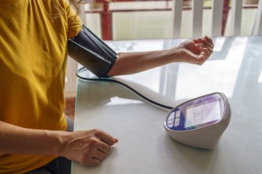 Endişeli Orta yaşlı kadın. Oturma odasında kan basıncını ölçüyor.