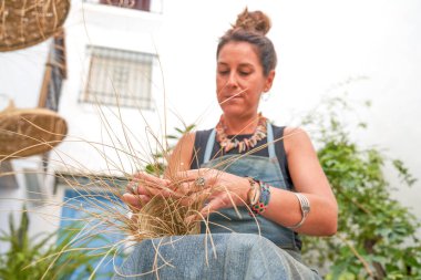 İspanyol kadının esparto lifli bir sepet ördüğü ön manzara. El işi, gelenek ve kültür.
