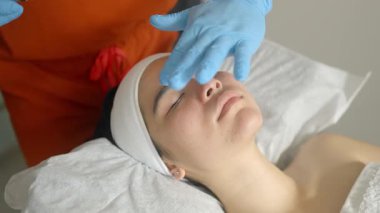 Becerikli güzellik uzmanları nazik yüz masajı yapıyor, nemlendirici tedaviyi uygularken müşteriler profesyonel cilt bakımı sırasında gözleri kapalı dinleniyor.