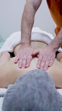 Profesyonel masör, kadın hastaya terapötik sırt masajı yapıyor. Sağlık spa tedavisinde rahatlama ve kas gerilimi desteği sağlıyor.