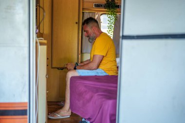 Orta yaşlı gezgin yaz kampı gezisi sırasında araçta uzanırken akıllı telefondan mobil oyun oynuyor.