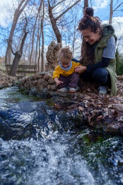 Anne ve oğul doğada güzel bir günün tadını çıkarıyorlar. Ormandaki bir nehrin tatlı suyuna dokunuyorlar.