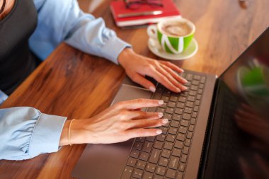 Uzaktan kumandalı serbest çalışan, kahve yudumlarken dizüstü bilgisayarda yazan, üretkenliğe odaklanmış rahat bir ev ofisi ortamı yaratan bir profesyonel.