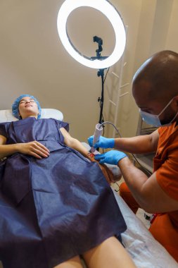 Kozmetik tedavisi sırasında kadın hastanın kolundaki lazer teknolojisi ile tıbbi profesyonellerin dövmeyi kaldırması.