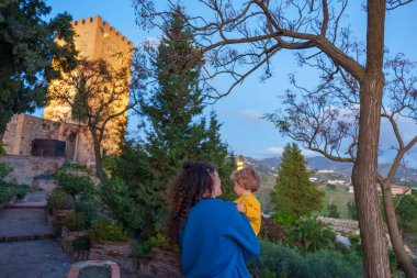 Bebekle birlikte Anne, Günbatımında Eski bir Müslüman Kalesini Gezi Turu sırasında Ziyaret Ediyor