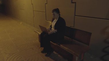 Gece tren istasyonunda dizüstü bilgisayarda yazan genç bir kadın. 