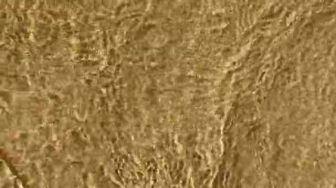 Kum üzerindeki sığ su dalgaları İspanya 'nın Mallorca kentindeki güneşli bir sahilde güzel desenler oluşturur.