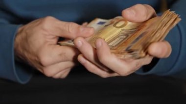 Şirket ortamında profesyonel nakit yönetiminin resmedildiği önemli miktarda 50 avroluk banknotla ilgilenen işadamı