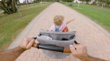 Baba ve bebek arabası parkta yürüyor. 