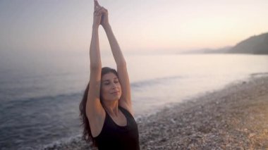 Yoga uzmanlığı, sabah vakti çakıllı sahil şeridinde meditasyonla asana egzersizi yapmak, özenli hareketlerle refahı ve iç huzuru somutlaştırmak.