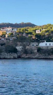 Mallorca kıyı şeridi sınırındaki el değmemiş beyaz binalar turkuaz Akdeniz sularına demirlemiş lüks yatlar parlak yaz güneşi ışığı altında.