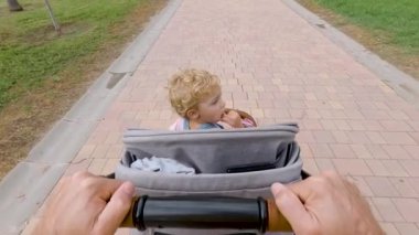 Baba ve bebek arabası parkta yürüyor. 