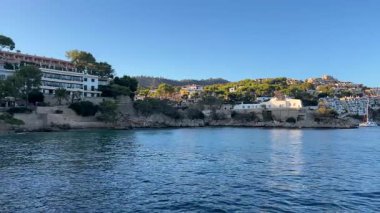 Sakin sular, berrak mavi gökyüzünün altında yemyeşil bir ortamda yuva yapmış büyüleyici binalar sergiliyor.