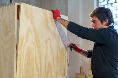 Orta yaşlı İspanyol marangoz, marangozhanesinde bir mobilya montajında çalışıyor.