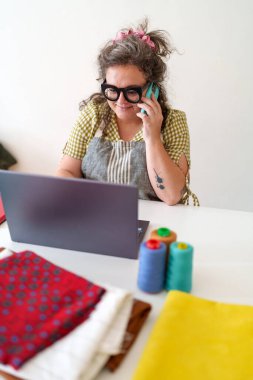 Dikişçi çoklu görev, dizüstü bilgisayarda çalışırken telefonla konuşmak, küçük işletme siparişlerini yönetmek ve lojistik dağıtımı