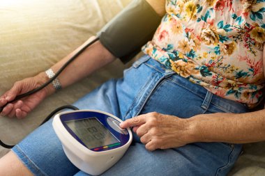  Tansiyonu evde ölçülen tanınmamış yaşlı kadın. Evde Kan Basıncını Ölçen İspanyol Yaşlı Kadın SağIık ve Sağlık İçin Dijital İzleyici Kullanıyor.