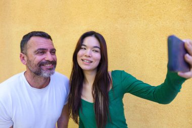 Mutlu çoklu etnik aile mutlu bir anın tadını çıkarırken akıllı bir telefonla selfie çekiyorlar, açık havada sevgilerini ve bağlantılarını yakalıyorlar.