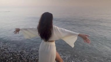 Uzun saçlı esmer, altın güneş doğarken çakıl taşlı sahilde zarif bir şekilde dans ediyor. Zarif bir hareketle özgürlüğü ve huzuru temsil ediyor.