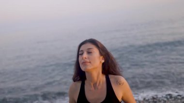 Huzurlu gündoğumu sırasında kıyı şeridi boyunca dikkatli nefes alma ve zarif kol hareketleri konusunda deneyimli yoga uzmanı.