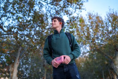 Dışarıda elinde antika bir walkmanle duran, kulaklığı takan ve müzik dinleyen genç bir adam. Gençliğin nostaljisini ve klasik ses teknolojisini vurguluyorum.