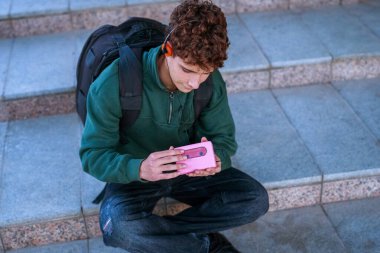 Klasik müzik seti ve kulaklıkla granit basamaklarda oturan genç. Retro ses teknolojisi yansıtılıyor