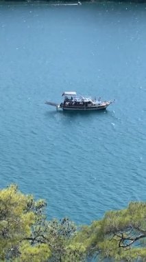 Fethiye 'deki muhteşem Ege Denizi' nde gezinen büyüleyici bir tekneye bakın. Türkiye 'nin Oludeniz kenti yakınlarındaki Babadag Dağı' nın yemyeşil tepeleri tarafından çerçevelenmiş güneşli ve görkemli manzaralı yolcular.