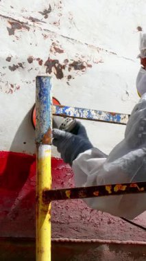 Yetenekli bir işçi, altındaki bozulmamış yüzeyi ortaya çıkarmak için eski boyayı titizlikle söker. Bu temel bakım, dayanıklılığı ve gelecek yolculuklar için cazip bir son sağlar..