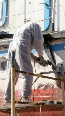 Kendini işine adamış işçiler harıl harıl çalışan tersanede geminin gövdesinden eski boya katmanlarını titizlikle sökerler. Dönüşüm, bu deniz gemilerinin korunmasında gösterilen çabayı vurguluyor.