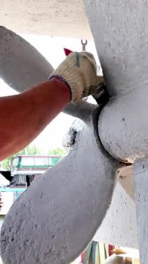 Yetenekli bir zanaatkar, canlı bir tersanedeki ana gemi pervanesine ustalıkla boya sürer. Atmosfer ustalık ve adanmışlıkla uğulduyor, deniz bakımının karmaşık detaylarını gösteriyor..