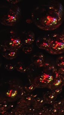 Pek çok parlak, renkli ve yansıtıcı kürelerin yakın çekimi. Kürelerin hepsi farklı boyutlarda ve görüntüye dağılmış durumda. Sahne bir merak ve hayranlık kaynağıdır. Dikey video..