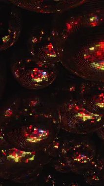 Bir grup yeşil ve kırmızı disko topu. Topların hepsi farklı boyutlarda ve görüntüye dağılmış durumda. Sahne enerjik ve eğlencelidir, çünkü disko topları genellikle partilerle ilişkilendirilir..