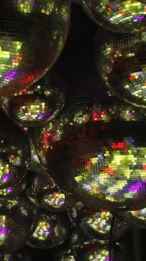 Parlak, renkli, yansıtıcı toplar. Topların hepsi farklı boyutlarda ve renklerde, ve hepsi ışığı yansıtıyor. Sahnenin eğlenceli, neşeli ve enerjik bir havası var..