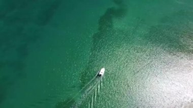 Didim, Akbuk Körfezi 'nde kristal berraklığında turkuaz su üzerinde tek bir teknenin baş aşağı görüntüsü. Bu minimalist, temiz kompozisyon seyahat, lüks içerik veya metin için arka plan olarak mükemmeldir. Barış, özgürlük ve yaz taşır.