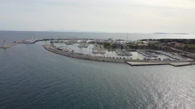 Saygın bir marina limanında demirli lüks yatlarla dolu sinematik hava aracı görüntüleri. Mavi körfezin bu çarpıcı manzarası deniz zenginliğini, turizmi ve yaz yaşam tarzını mükemmel bir şekilde gösteriyor..