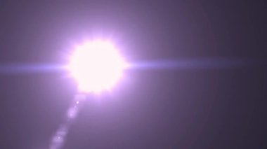 Parlak beyaz bir ışık kaynağı belirgin bir lens ile koyu mor ve gri eğimli bir arka plana işaret eder. Işık sahneye hükmediyor, güçlü bir odak noktası ve görsel ilgi yaratıyor..