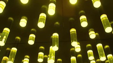 Tavandan sarkan silindirik ışıkların görüntüsü. Işıklar sıcak ve güzel bir ortam parlaklığı yaratıyor. Koyu tavan parlak ışıklarla çelişiyor. Modern iç tasarım.