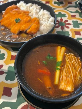 Baharatlı Tom yum çorbası, kıtır körili pilavın yanında servis edilir. Tatmin edici bir Asya füzyon yemeği yaratır. Restoran menüsü kullanımı, konforlu yemek görselleri, mutfak promosyonu ve yemek fotoğrafçılığı için mükemmel..