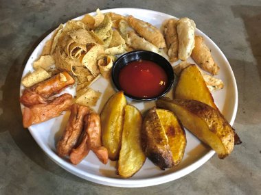 Tabakta patates, sosis ve sos bulunan kızarmış abur cubur tabağı. Rahatlatıcı yemek sunumu yemek ve gevşetilmiş yemek için uygundur..