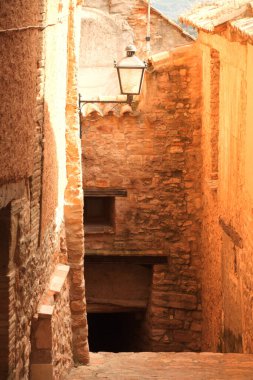 Kırsal duvarları ve eski bir feneri olan dar, taştan dar bir sokak..