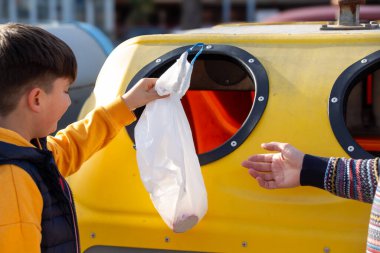 Çöpleri geri dönüşüm kutusuna atan çocuk..