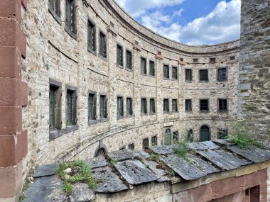 Ehrenbreitstein kalesi, eski pencereleri ve bulutlu gökyüzünün altındaki taştan cephesi olan eğimli taş bina.